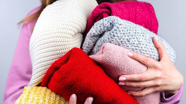 pila di maglioni colorati in mano