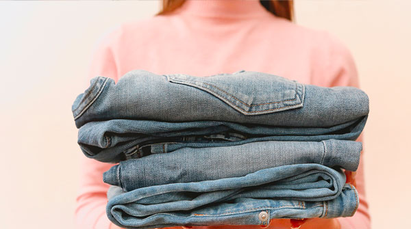 ragazza che tiene in mano jeans impilati
